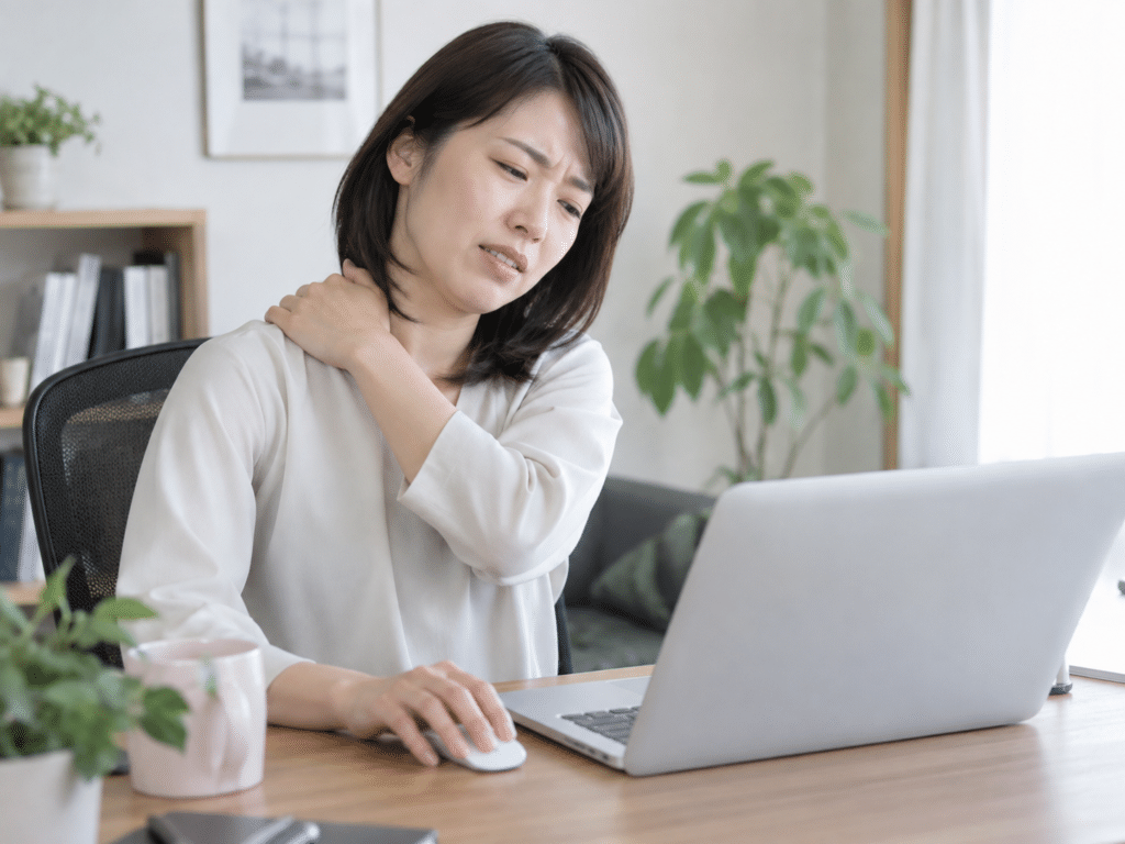 パソコン作業中に肩を押さえている女性